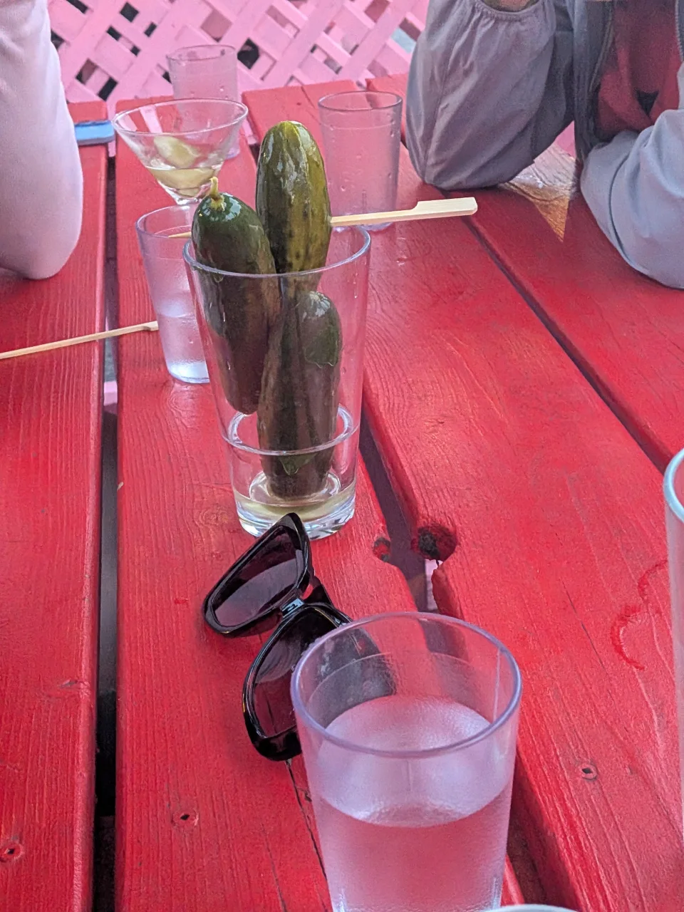 Three pickles served in a glass on a red picnic table at Uncle Abe's.